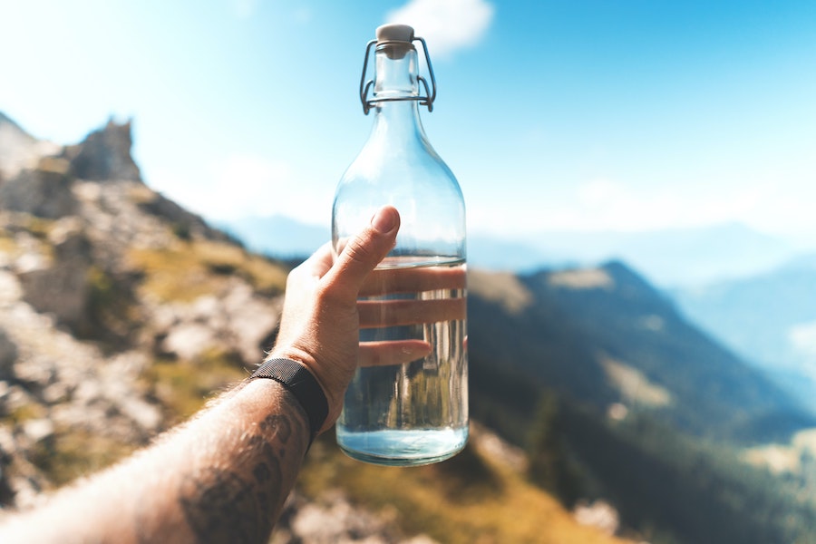 Bouteille d'eau en verre devant un paysage de montagne