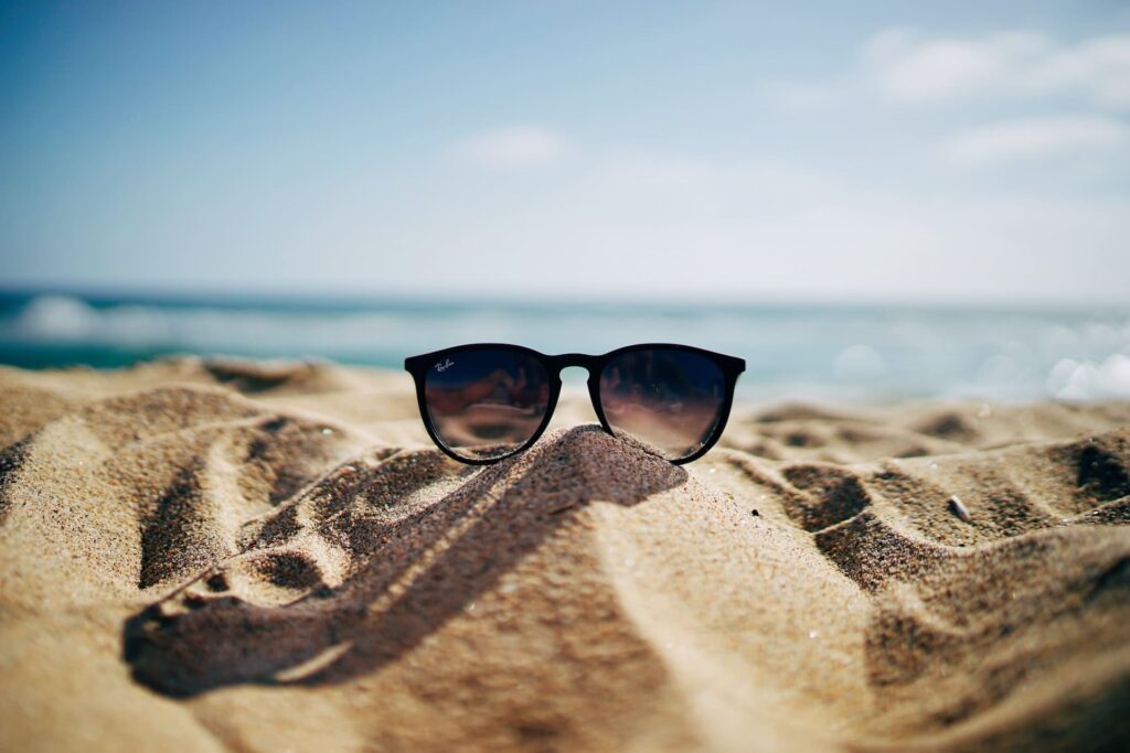 Paire de lunettes sur le sable au bord de la mer - partir en vacances, idées de destinations
